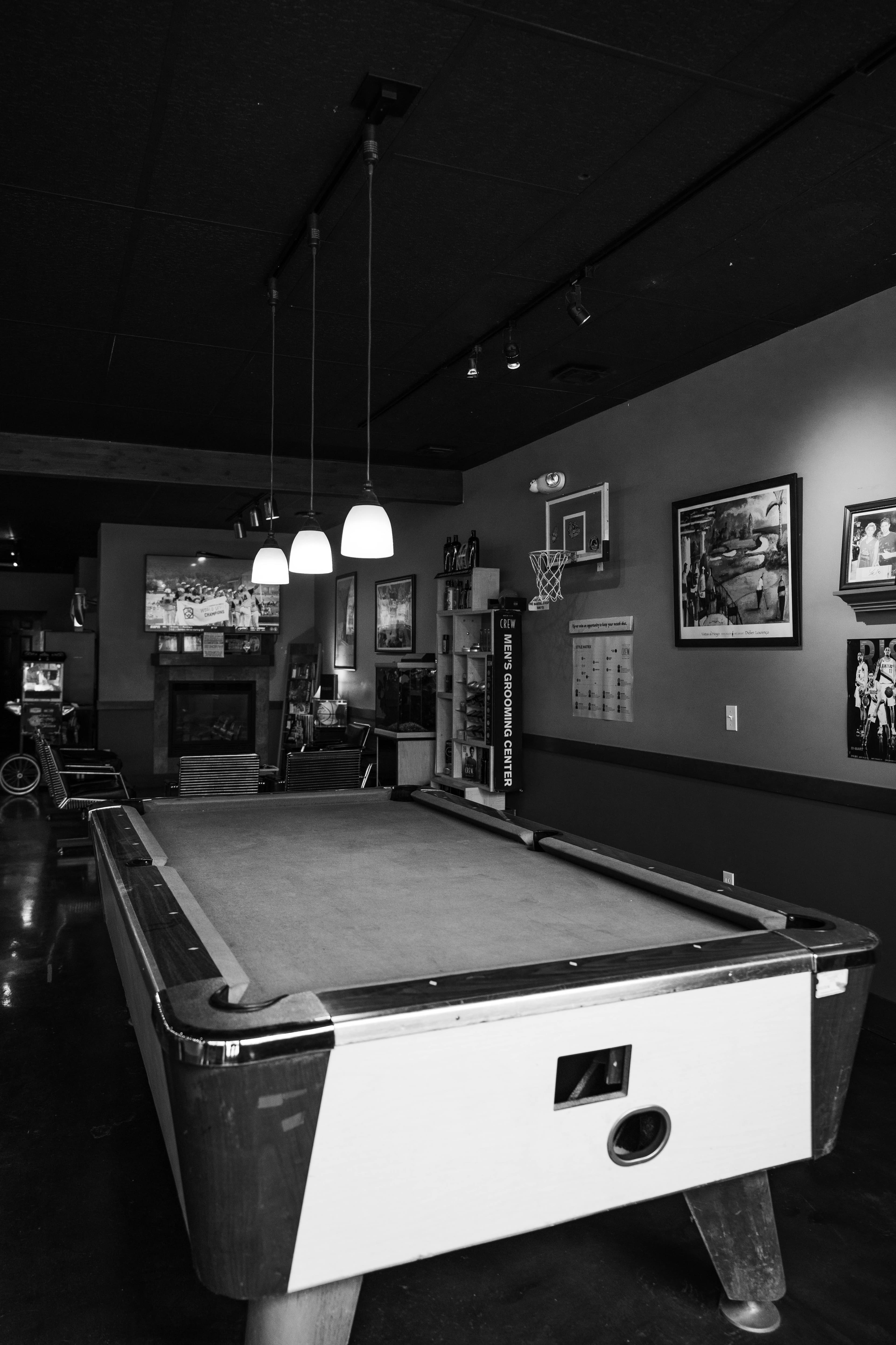 Pool table with pendant lighting and sports memorabilia on walls